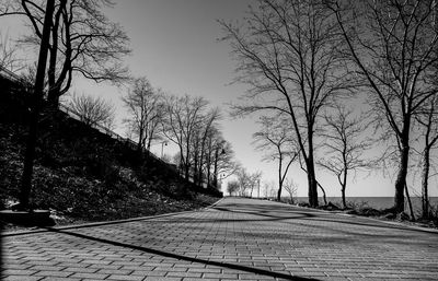 Road amidst bare trees against clear sky during winter