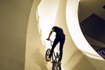 Reflection of man on bicycle against building