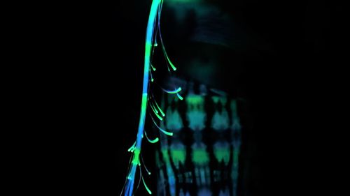 Close-up of illuminated chain swing ride against black background