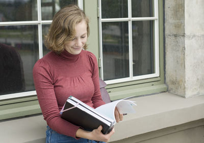 Young caucasian girl going back to college, school, standing with a notebooks