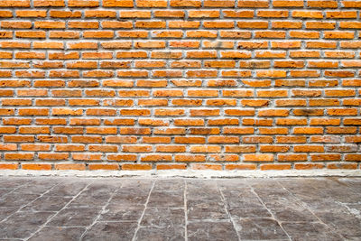 Empty footpath against brick wall