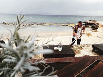 High angle view of man planting at beach against sky