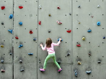 Rear view of girl climbing wall
