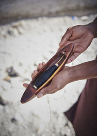 Midsection of person holding sewing item at beach