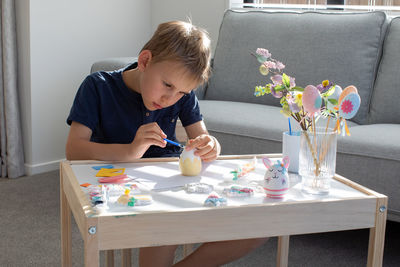 Side view of boy painting on table at home
