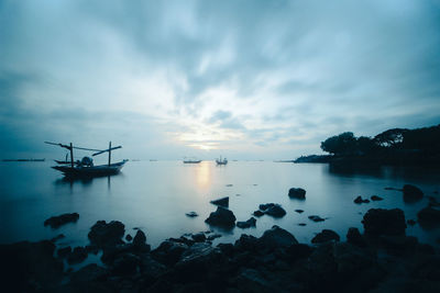 Silhouette boats in sea against sky