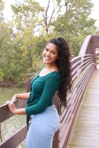 Portrait of young woman standing against a bridge 