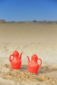 Close-up of red umbrella on sand at beach against clear sky