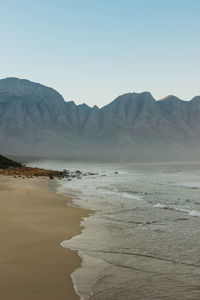 Scenic view of sea and mountains against clear sky