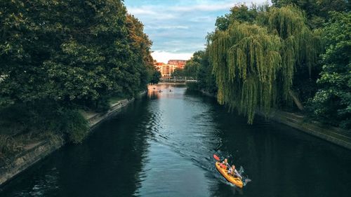 People kayaking on canal amidst trees