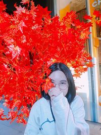 Portrait of woman standing by red flowering plants