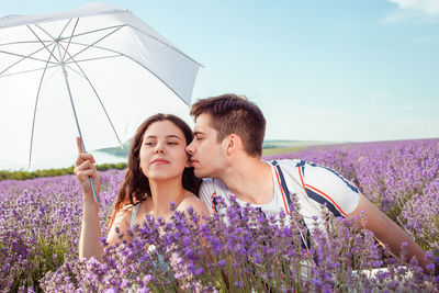 A couple in love under a white umbrella on a lavender field love