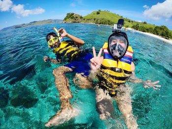 Portrait of friends gesturing while snorkeling in sea