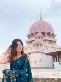 Young woman standing in sari against mosque