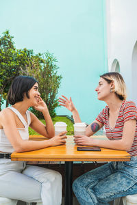 Side view of lesbian couple talking while sitting at outdoor cafe