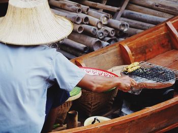 Rear view of man grilling meat on wooden boat