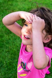 Close-up of smiling girl shielding eyes on field