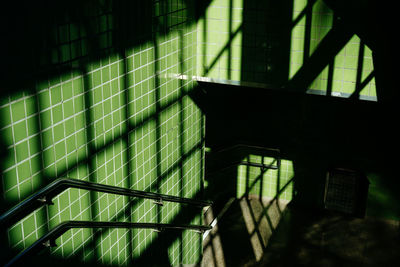 High angle view of shadow on green tile wall