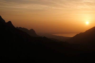 Scenic view of silhouette mountains against orange sky