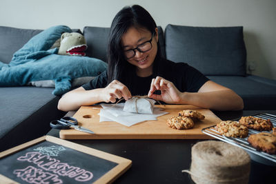 Smiling woman packing food sitting at home
