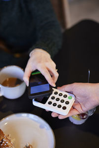 Young woman paying with phone in cafe