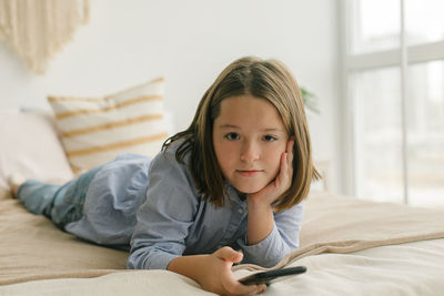 Young woman using mobile phone while lying on bed at home