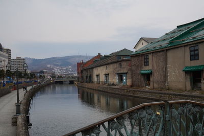 Buildings by river against sky in city