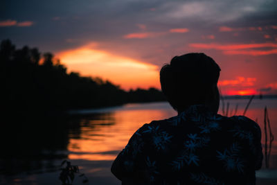 Rear view of silhouette woman standing against sky during sunset