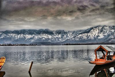 Scenic view of lake by snowcapped mountains against sky