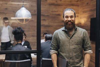 Portrait of smiling businessman with beard standing at doorway