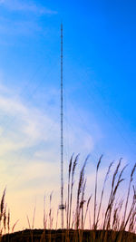 Low angle view of electricity pylon against sky during sunset