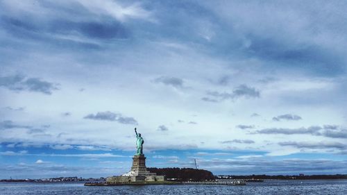 Statue in city against cloudy sky