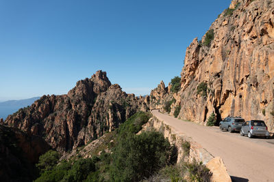 Road amidst rocks against clear blue sky