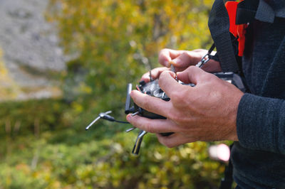 Male hands holding sticks on the remote control of a drone, close-up, outdoors