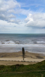 Scenic view of beach and groyne against sky