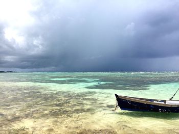 Boats in sea against cloudy sky