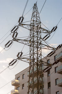 Low angle view of electricity pylon and buildings against sky