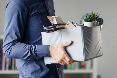 Midsection of man holding cardboard box in office