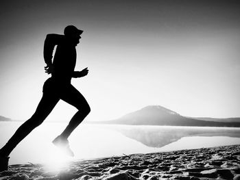 Silhouette man standing on mountain against clear sky