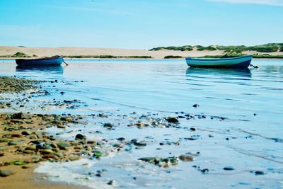 Boats moored on sea shore against clear sky