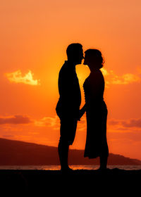 Couple kissing at beach, silhouette in sunset, love and friendship.