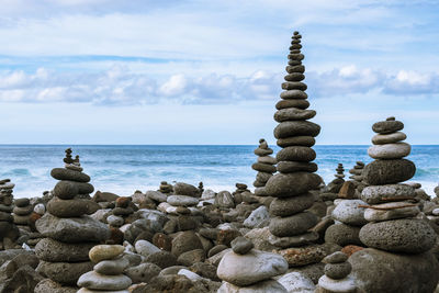 Stack of stones in sea against sky