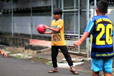 Full length of boys playing with ball in city
