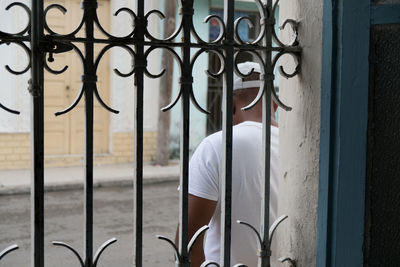 Man standing by metal gate against window