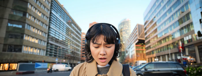 Portrait of young woman standing in city