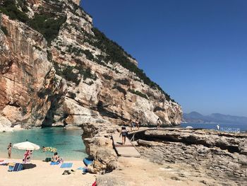 People at beach against clear blue sky