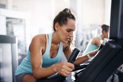 Young woman using mobile phone while sitting at gym