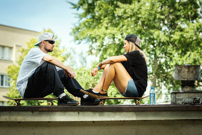 Friends sitting on plant against trees