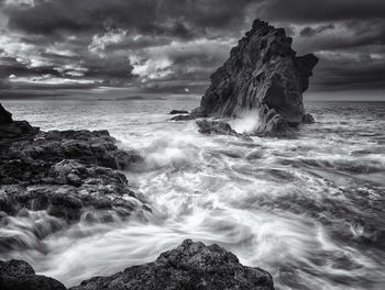 Rock formations in sea against cloudy sky at madeira