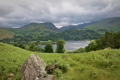 Scenic view of lake and mountains against stormy sky